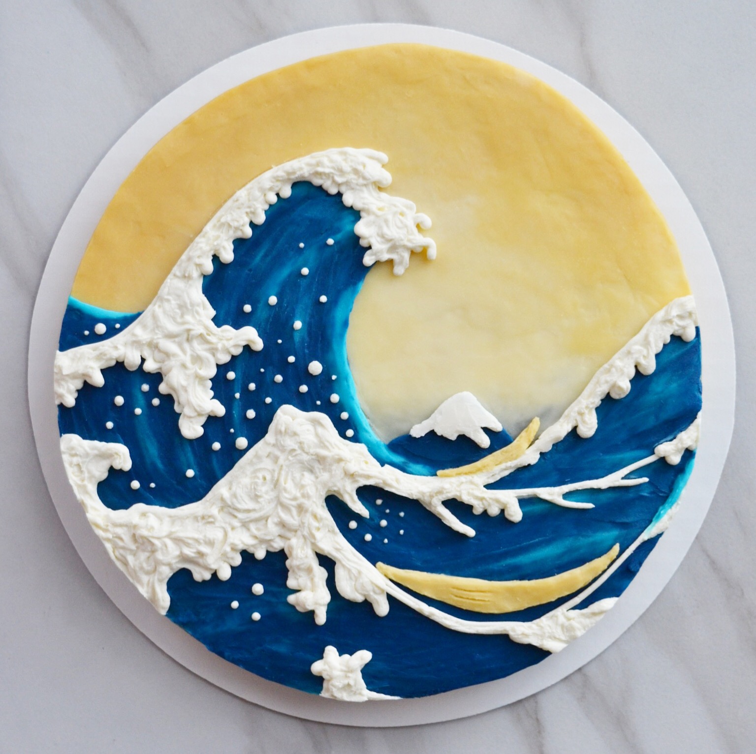 Top-down shot of a circular cake decorated to look like the Great Wave over Kanagawa