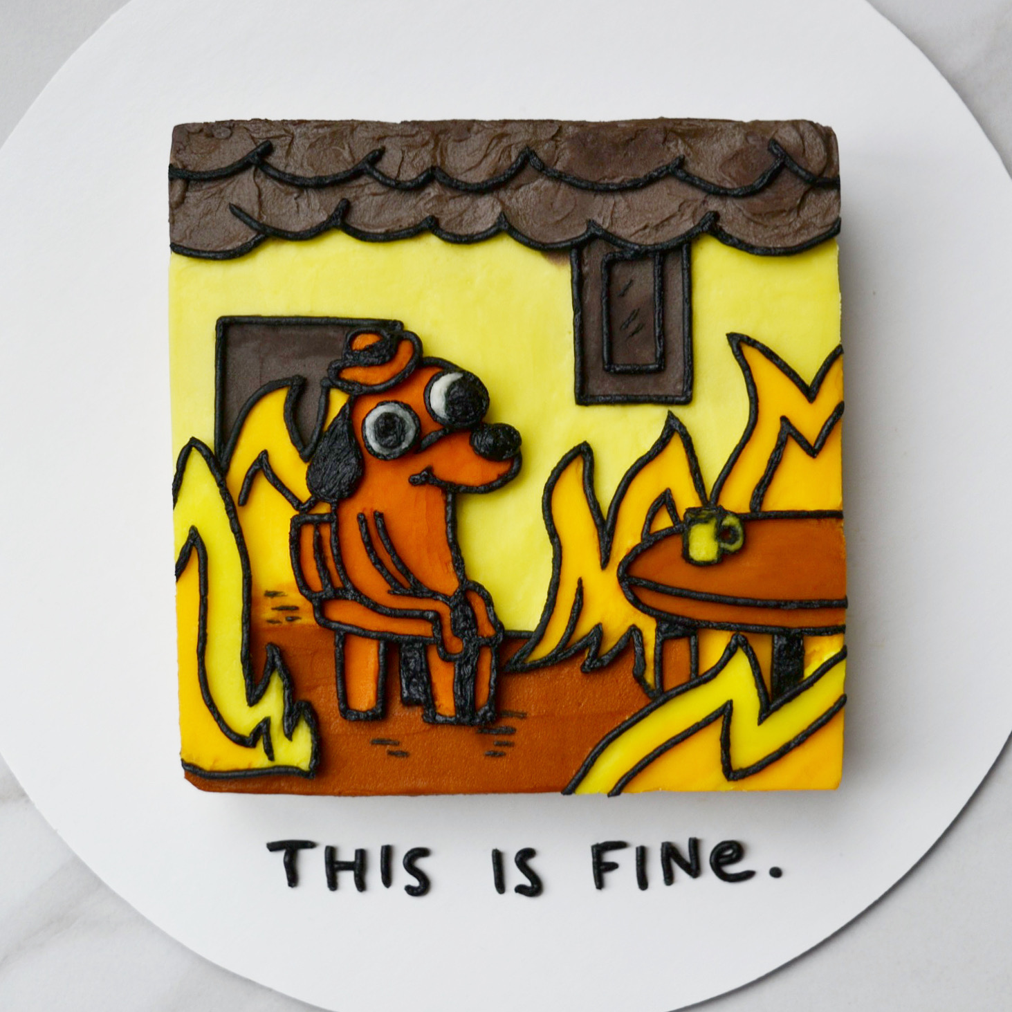 Top-down shot of a square cake decorated to look like the 'This Is Fine' meme